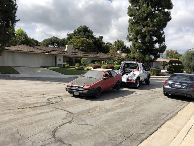 Budget Towing truck towing a classic Toyota Corolla